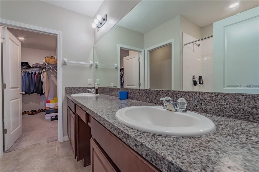 Primary on-suite bathroom with shower, dual sinks, and separate stall.