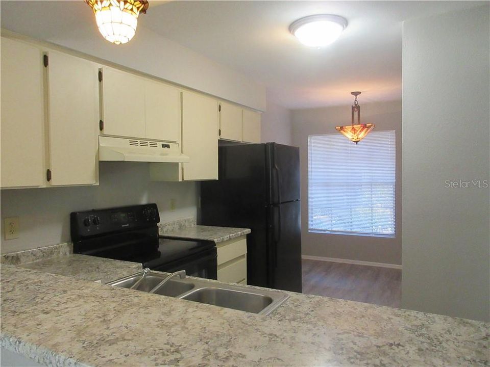 Kitchen has updated countertops and black appliances; casual dining area with lovely fixture