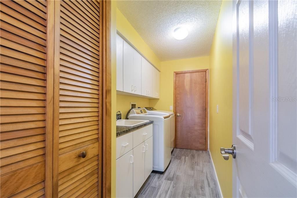 INDOOR LAUNDRY WITH PLENTY OF CABINETS AND A DEEP UTILITY SINK