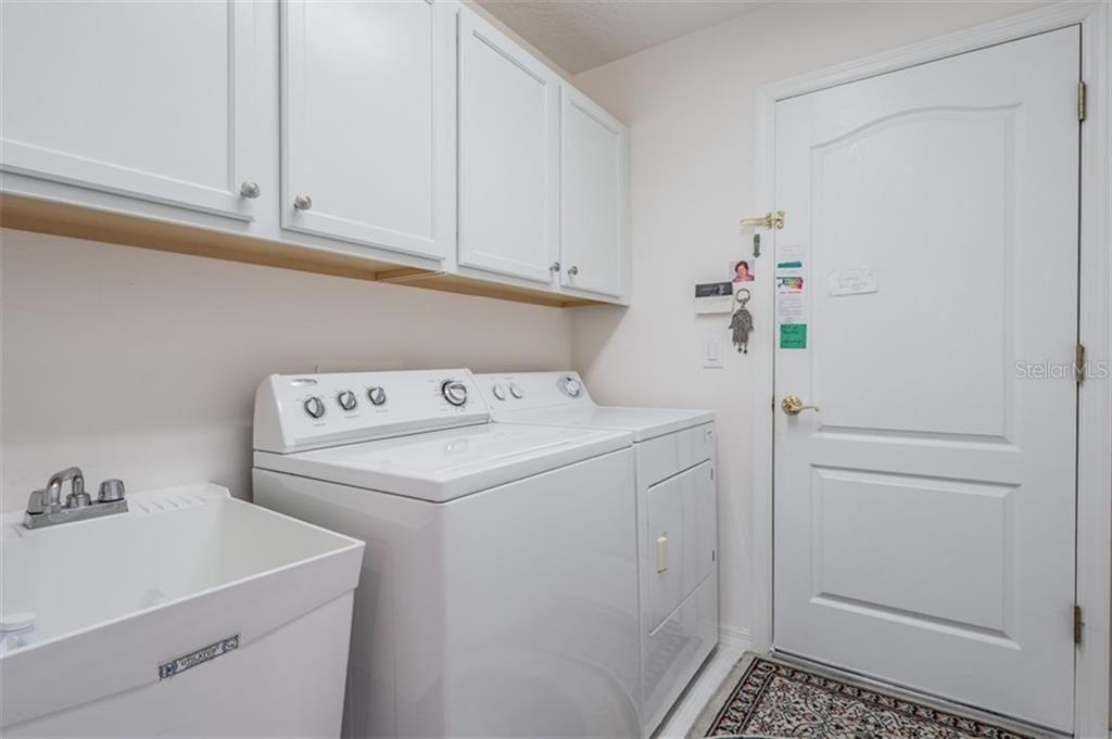 Walk-in laundry room with built in cabinets and utility sink