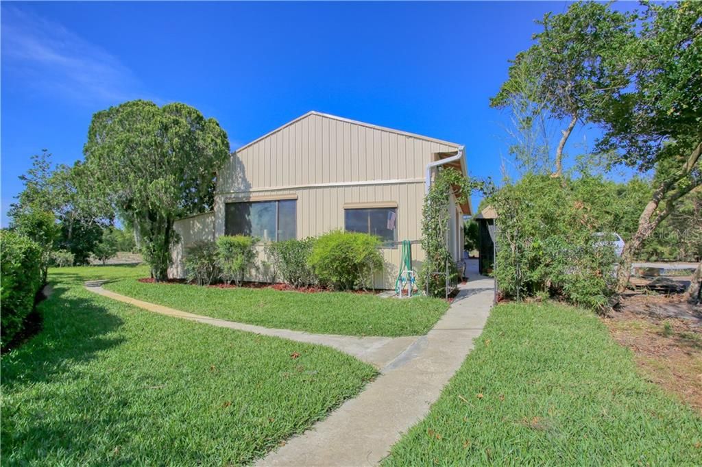 Lushly landscaped and paved walkway between workshop and home