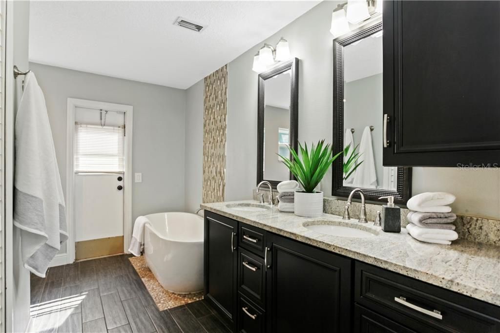 Renovated Owners' En-Suite features double sinks, granite counters, free-standing soaking tub and access to the pool.