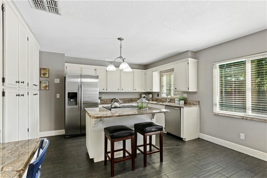Kitchen features a cooking island, granite counters, pantry, built in desk and stainless appliances.