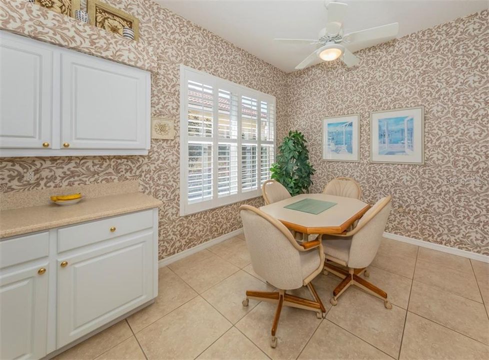 Casual eating area in kitchen has a large window with plantation shutters.