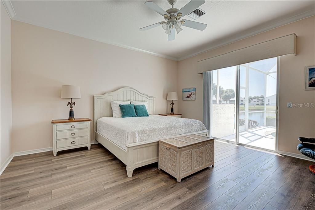 Large master bedroom has tranquil lake views, a slider for easy lanai access and crown molding.