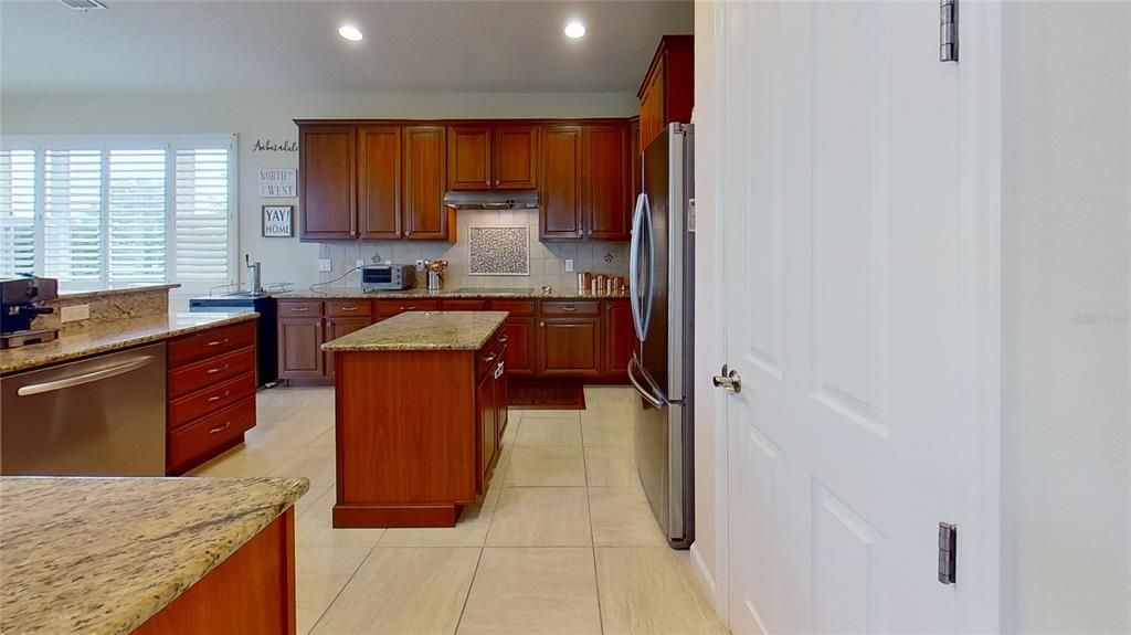 This kitchen has an island, pantry, and stainless steel appliances.