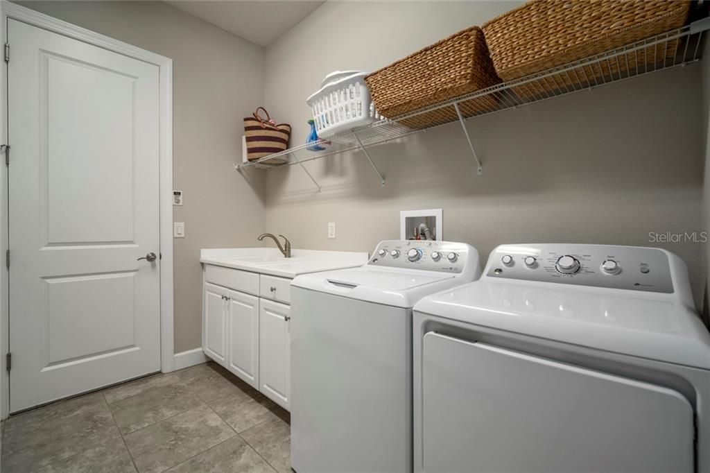 Huge laundry with counter for folding, cabinets and utility sink.