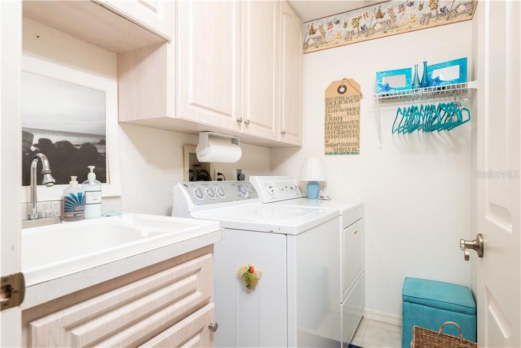 Laundry room features extra storage cabinets and sink