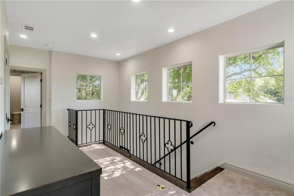 The wooden stairs with custom iron railings lead you upstairs to landing and three additional bedrooms