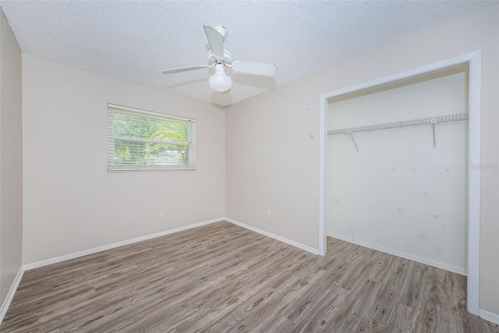 Third bedroom with ceiling fan and vinyl plank flooring