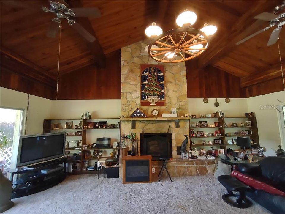 High Cathedral Ceilings in the Living Room with wood burning fireplace and built in shelving.