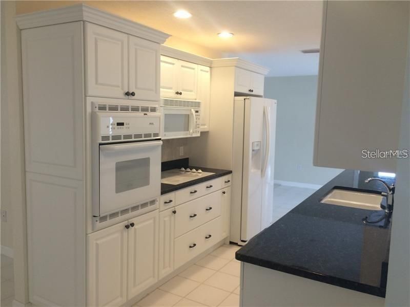 The kitchen features a built in wall oven, flat top range, microwave, refrigerator and dishwasher.