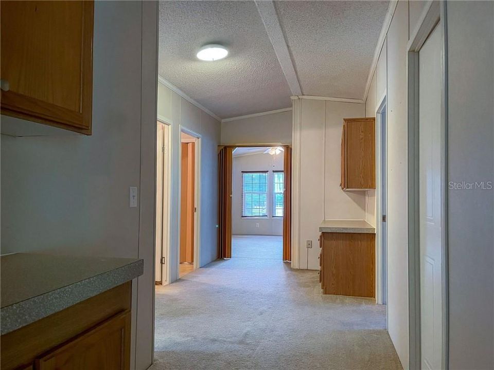 Hallway leading to 3 bedrooms, bathroom, family room, utility room & study/den area with built in desk area.