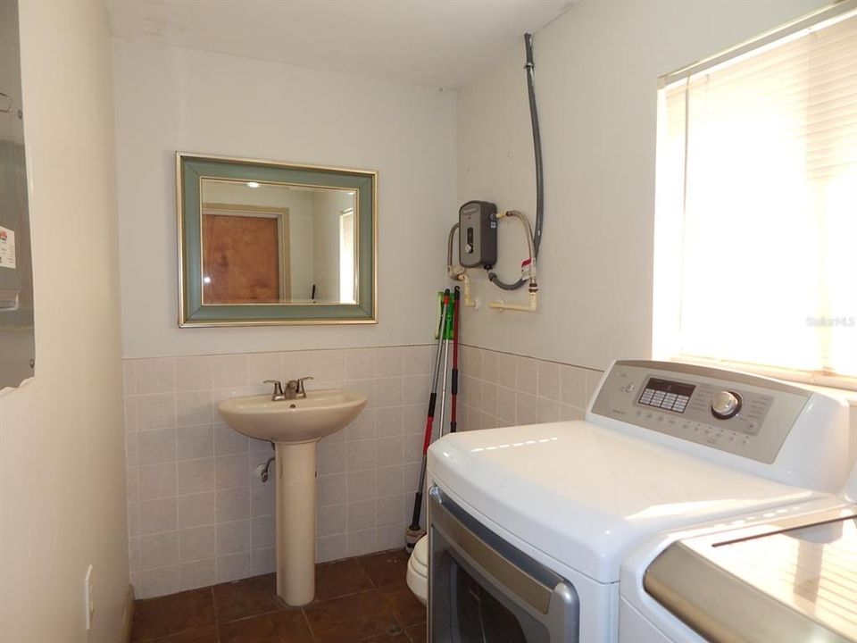 Inside utility room with on demand hot water heater and half bath.