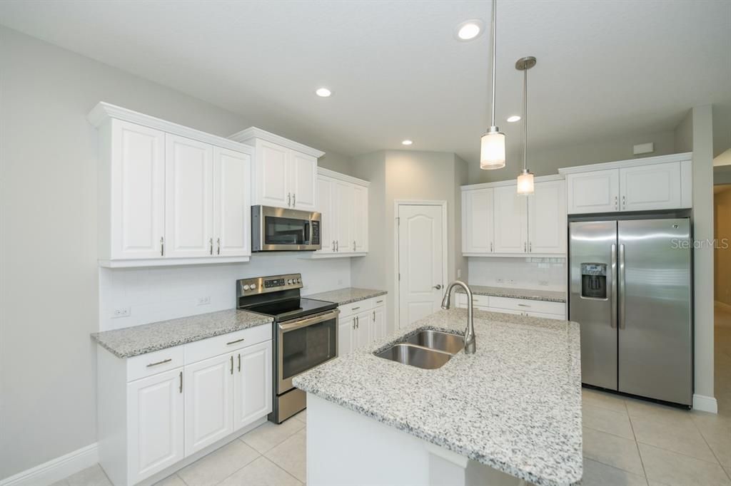 Granite counters, white cabinetry, and stainless steel appliances