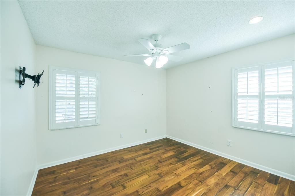 Additional bedroom offers wood floors, tons of natural light, plantation shutters on both windows and large closet.