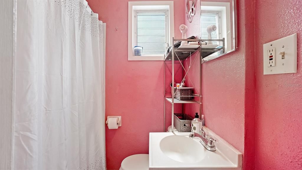 One bedroom unit bath room in a vibrant pink color