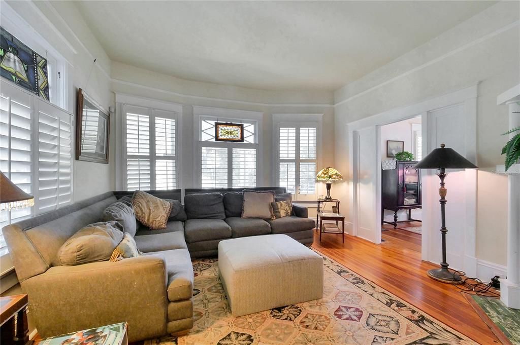 Updated with plantation shutters in this spacious living room that includes one of the fireplaces.