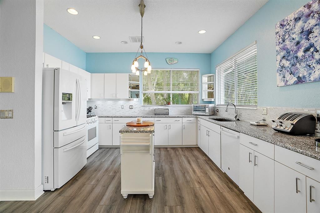 The recently updated kitchen has loads of storage, a prep-island, a beautiful glass backsplash, a gas range, a walk-in pantry, and a built-in desk.
