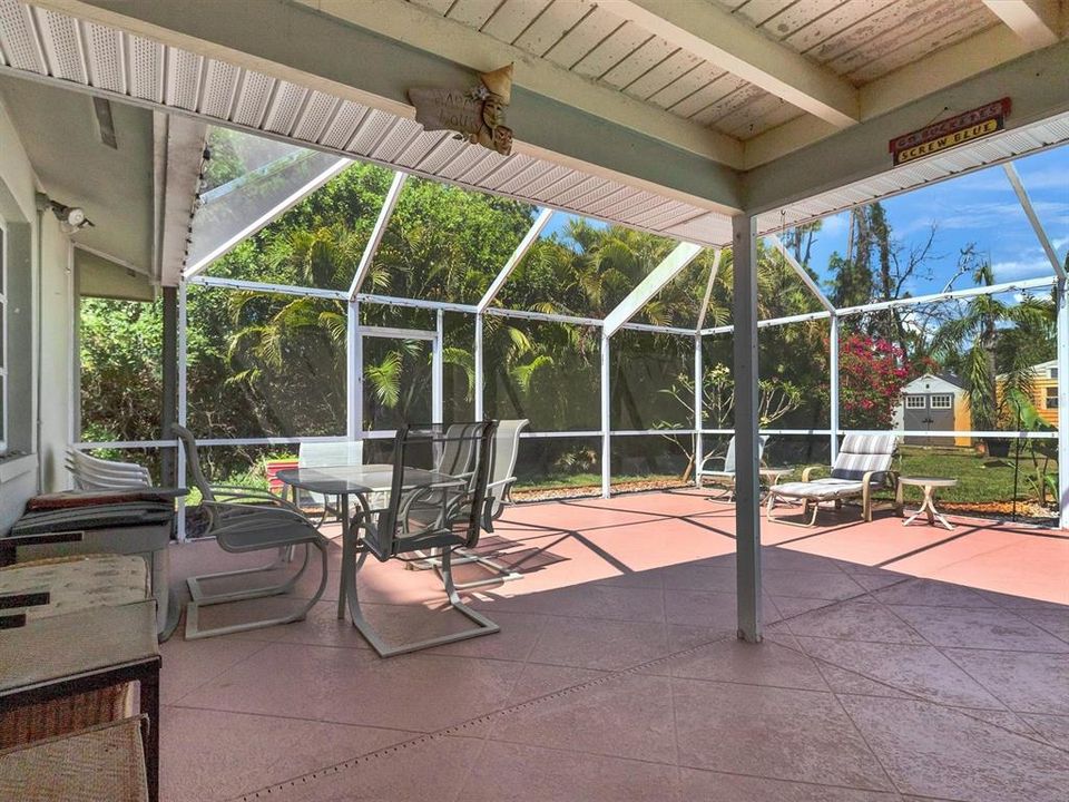 Extensive outdoor living space with covered and uncovered spaces within the screened cage.