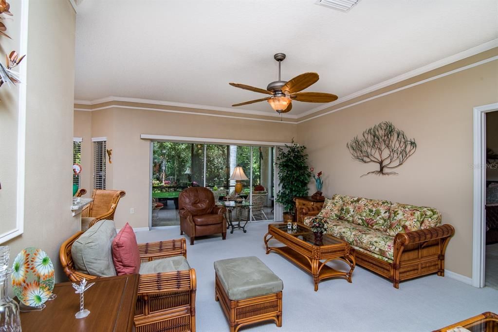 The living room has a designer ceiling fan with up-light and quality carpeting.