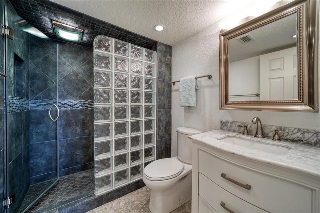 Guest bathroom features walk in tile shower and new vanity with granite counter