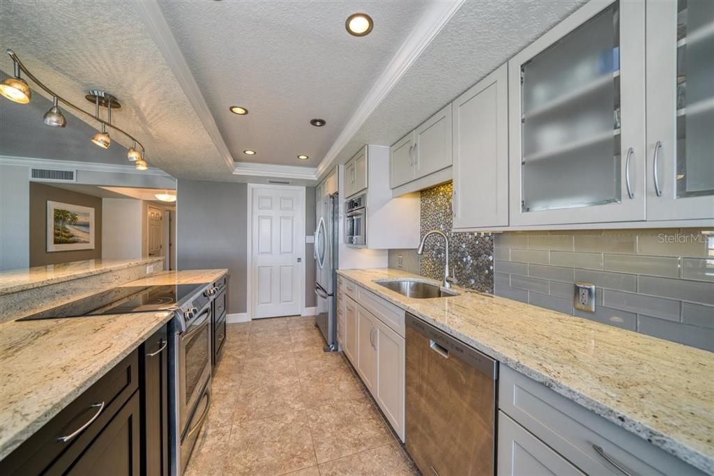 Kitchen features granite counters, solid wood cabinetry, stainless steel appliances, stainless and glass subway tile backsplash, large sink