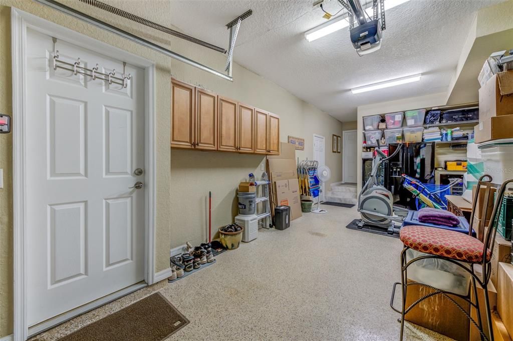 The garage has an epoxy-coated floor, abundant cabinets, large storage spaces and two pedestrian entrances directly from the home. The tall black refrigerator and the 4-ft. wine cooler at the back of the garage will convey with the home.