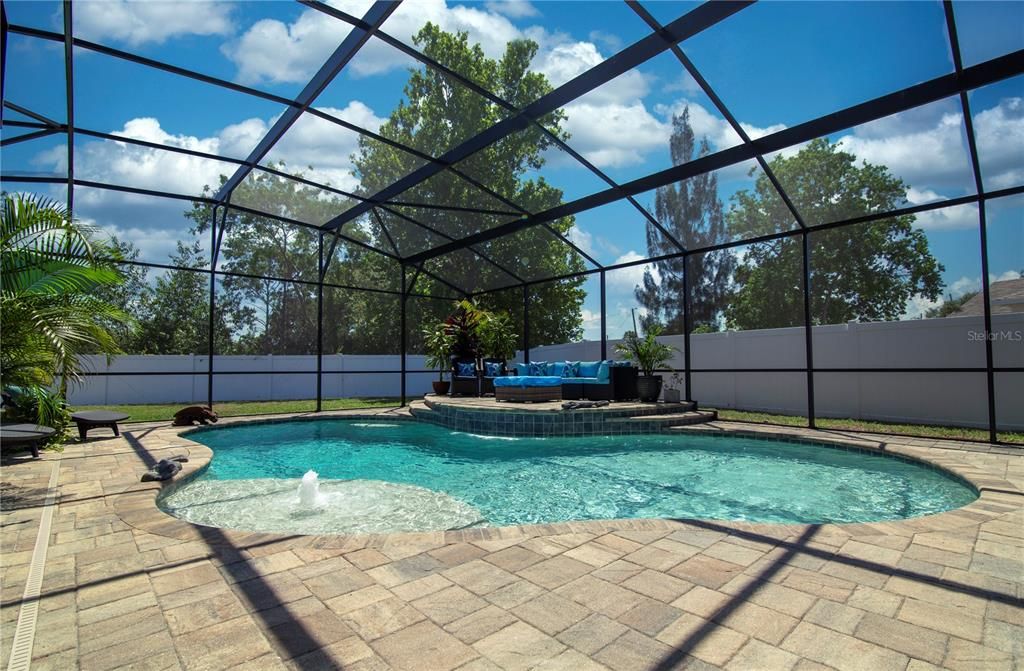 18,000 gallon aqua blue salt water pool with bubbler and 6 foot wide waterfall all nestled within a 6 foot privacy fence surrounding the entire back yard.