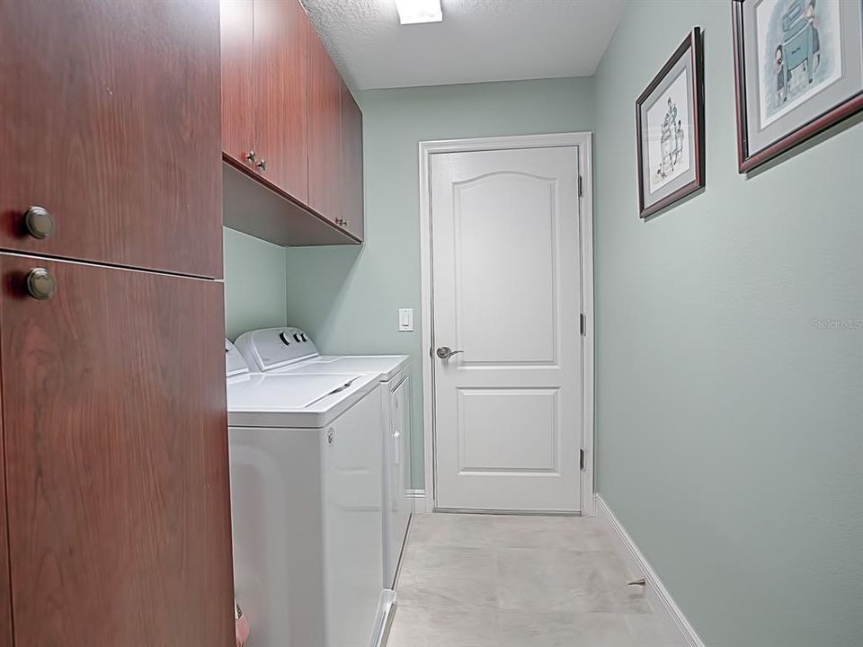 THE INDOOR LAUNDRY ROOM HAS PLENTY OF CABINETS FOR EXTRA STORAGE SPACE