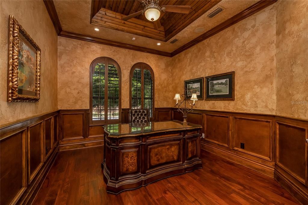 Wood floors, wood tray ceiling, wood wainscoting, and Plantation Shutters make this an office to make working from home a joy!