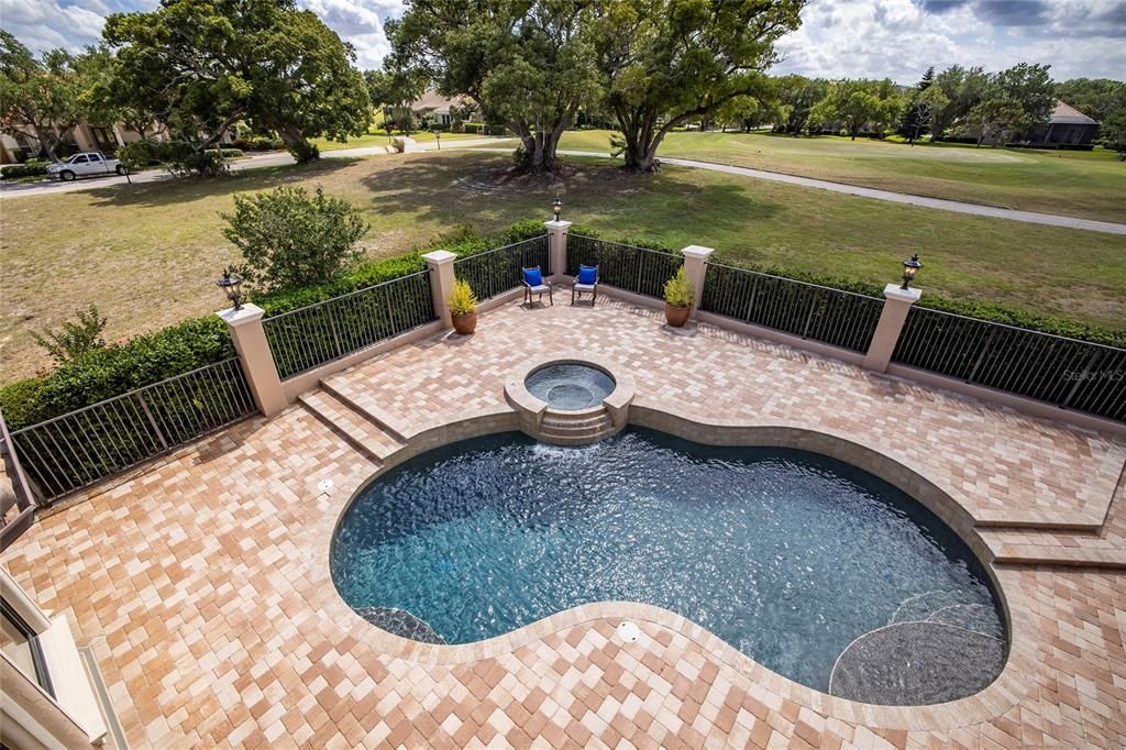 View of pool and 10th green of the Osprey South golf course from the second story balcony off of the second floor bonus room. A hedge of bushes around the pool perimeter add privacy to the pool area.