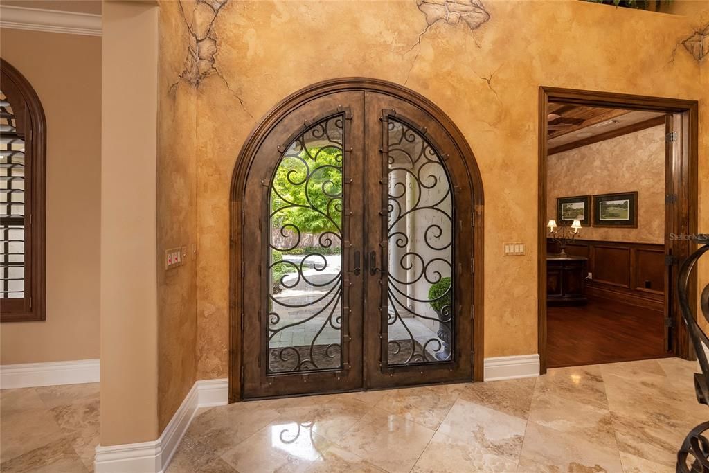 Custom hand forged entry doors and hand applied Venetian plaster adorn the foyer.  A chandelier hangs from the 21 foot ceiling with an electric pulley installed for lowering the chandelier to clean.