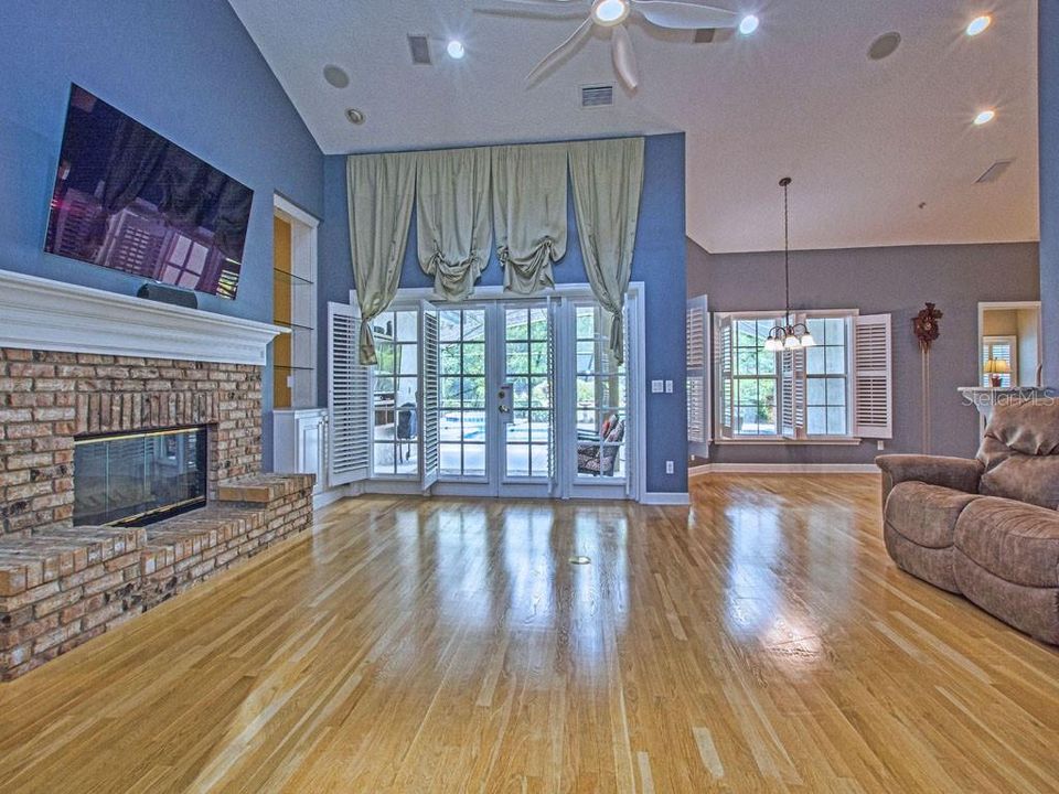 The great room has a vaulted ceiling, hardwood flooring, and french doors leading to the pool area.
