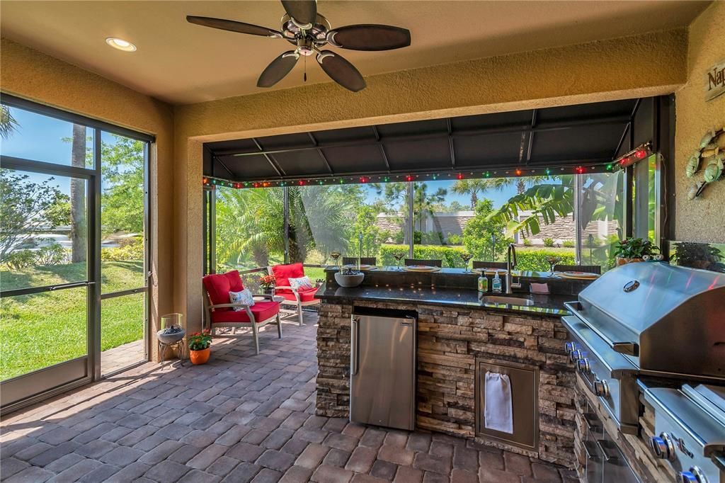 Full outdoor kitchen with stone faced exterior, automatic retractable awning, gas grill and double side burners, sink, refrigerator and storage. Sealed paved 16X16 lanai and side entrance door.