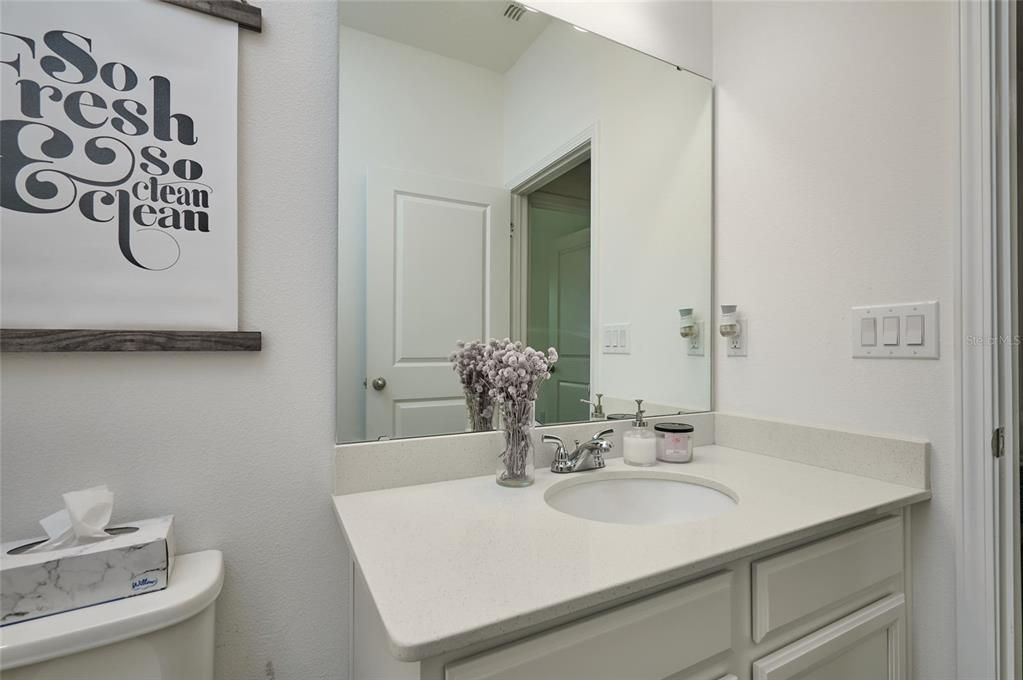 Solid surface counters are featured in the full guest bathroom