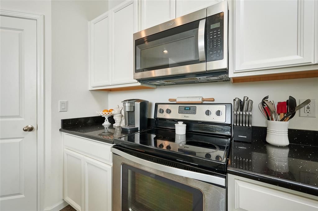 Stainless steel appliances accent the black granite countertops