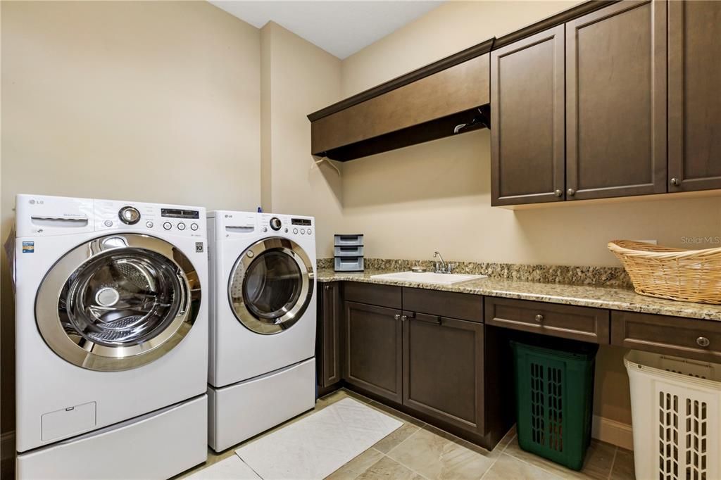 Spacious laundry room with full size utility sink, plenty of cabinet and counter space.  Washer and Dryer stay!