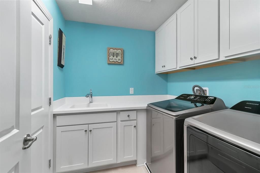 A FULL LAUNDRY ROOM W/ A UTILITY SINK and CABINETRY