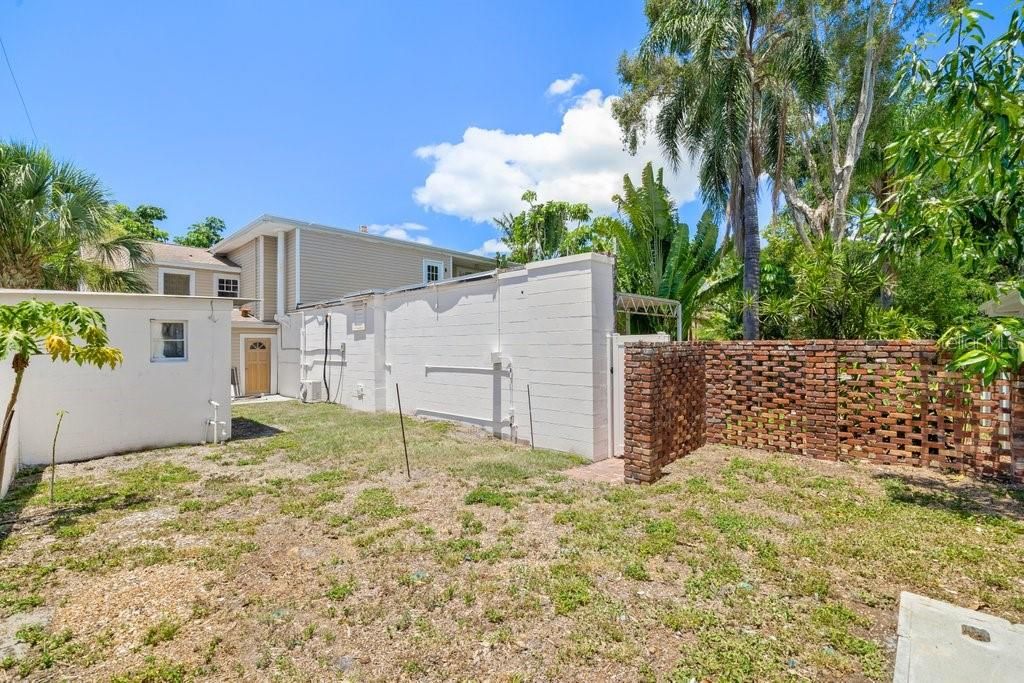 The Potting shed or additional storage is the building to the left and the brick wall leads back to the pool. This is a fenced area great for pets or you have access for boat or RV, if desired, from the alley access.