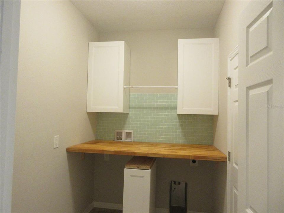 Laundry room with cabinets, tiled backsplash and butcherblock folding counter
