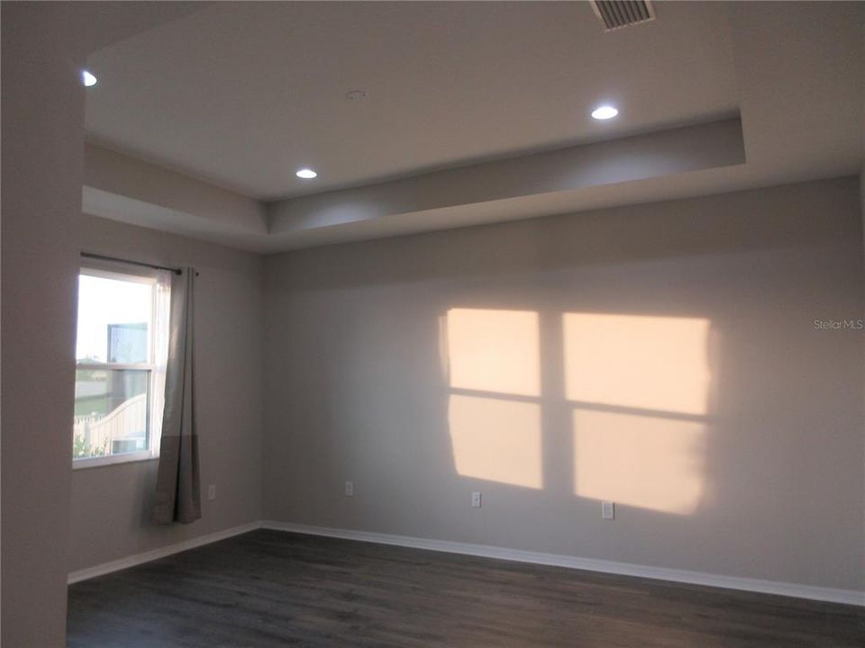 Master bedroom with tray ceiling and laminate floor