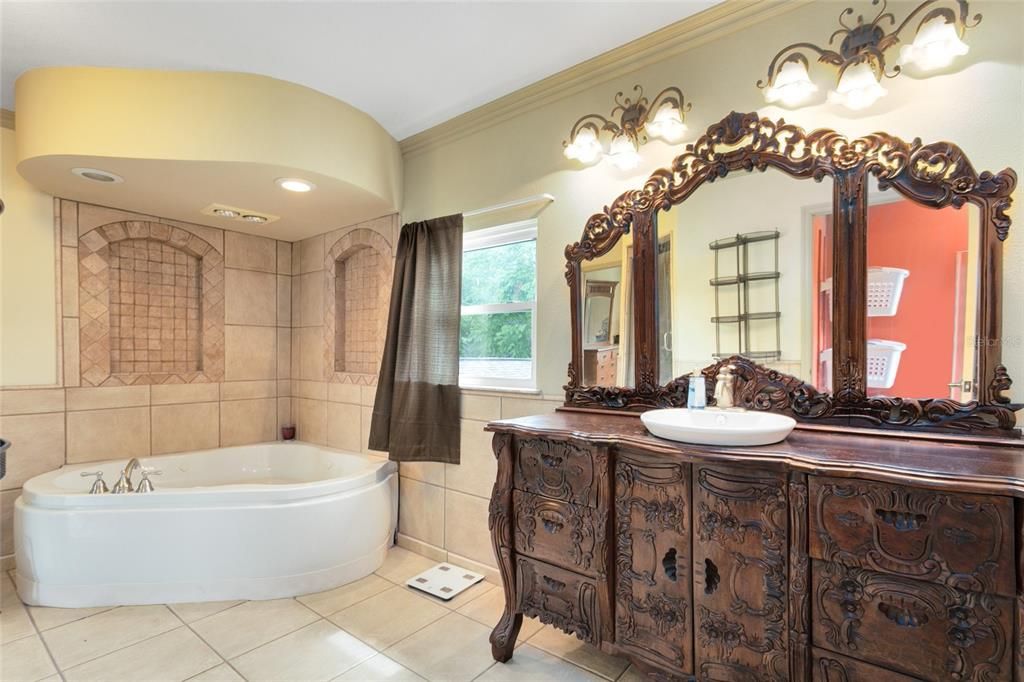 A ornate antique look vanity features a vessel sink, slid into the LUXURIOUS spa tub and wash your cares away!