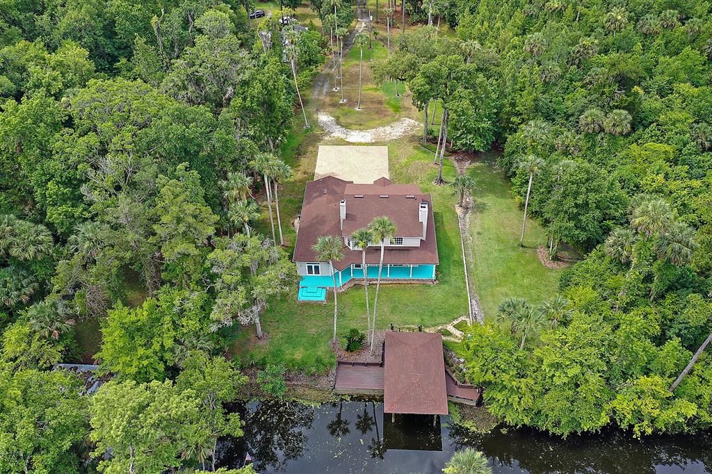 birds eye view of home orientation to canal.  The property is cleared and manicured around the house and the property on right is remaining wooded acreage for a total of 5.5 acres +-