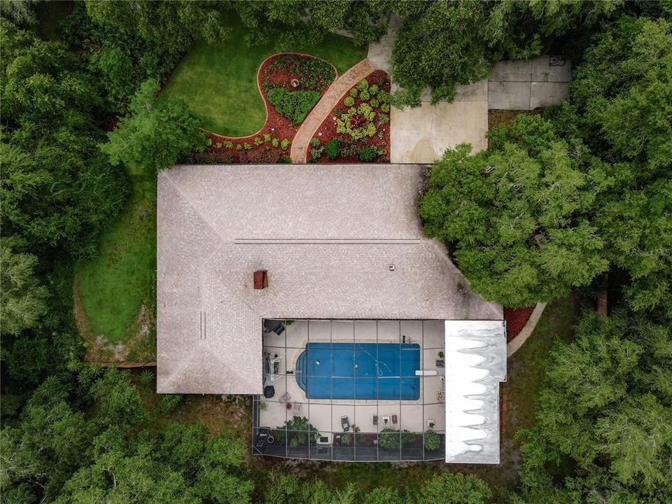 Aerial view showing the beautiful landscaping in the front yard and the large screened pool/lanai at the back of the home.