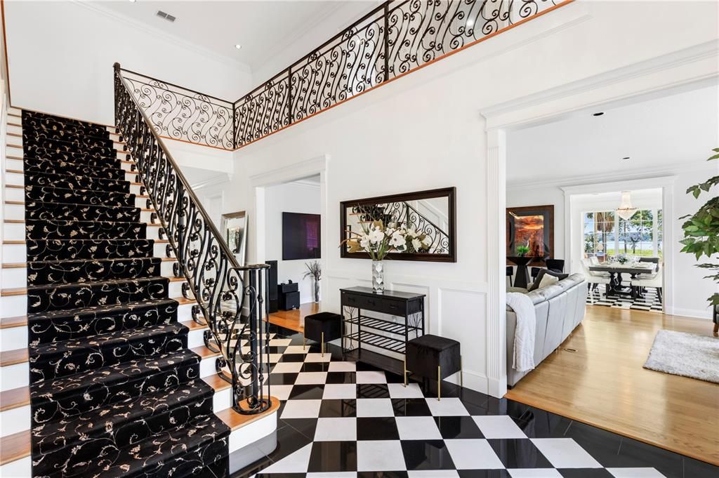 This view features the spectacular stair case with custom wrought iron Blasters along a view into the family room.