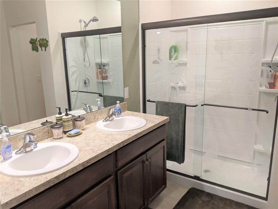 the master bathroom is bright and light with double vanities, walking shower with exquisite sliding door