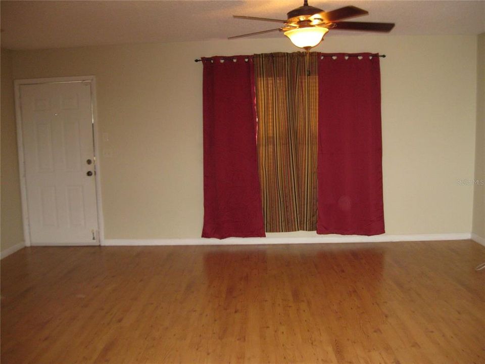 SPACIOUS LIVING ROOM WITH WOOD FLOOR AND CEILING FAN WITH LIGHT.