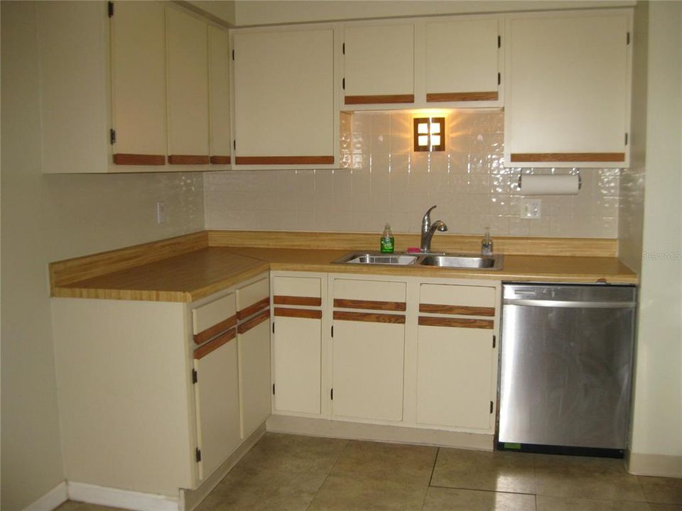 KITCHEN SHOWING DOUBLE STAINLESS STEEL SINK, D/W AND VINYL FLOOR.