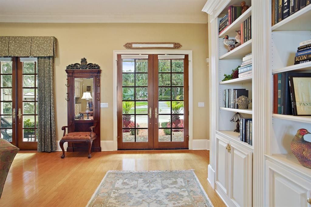 Double French doors open into the comfortably elegant great room with high, coffered ceiling, crown moldings, and wide baseboards.